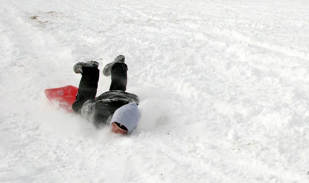 Person som åker pulka och landar på ansiktet i snön